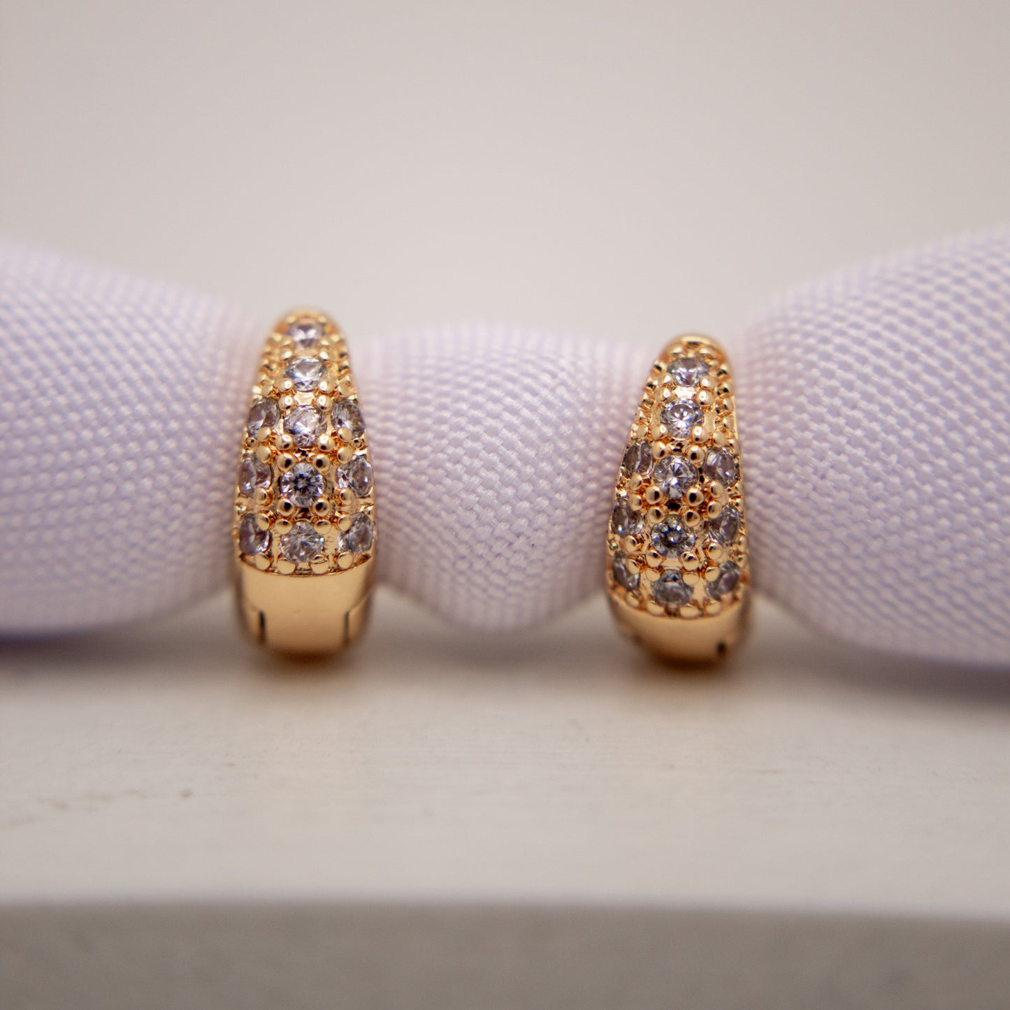 Gold hoop earrings with gemstones on a white background