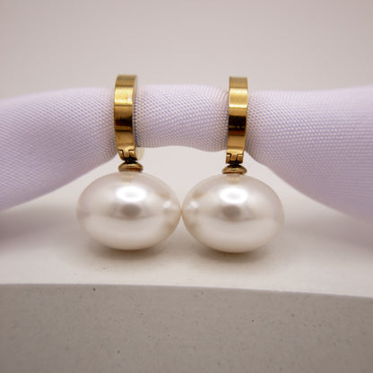 Pearl earrings with gold clasps on a white surface