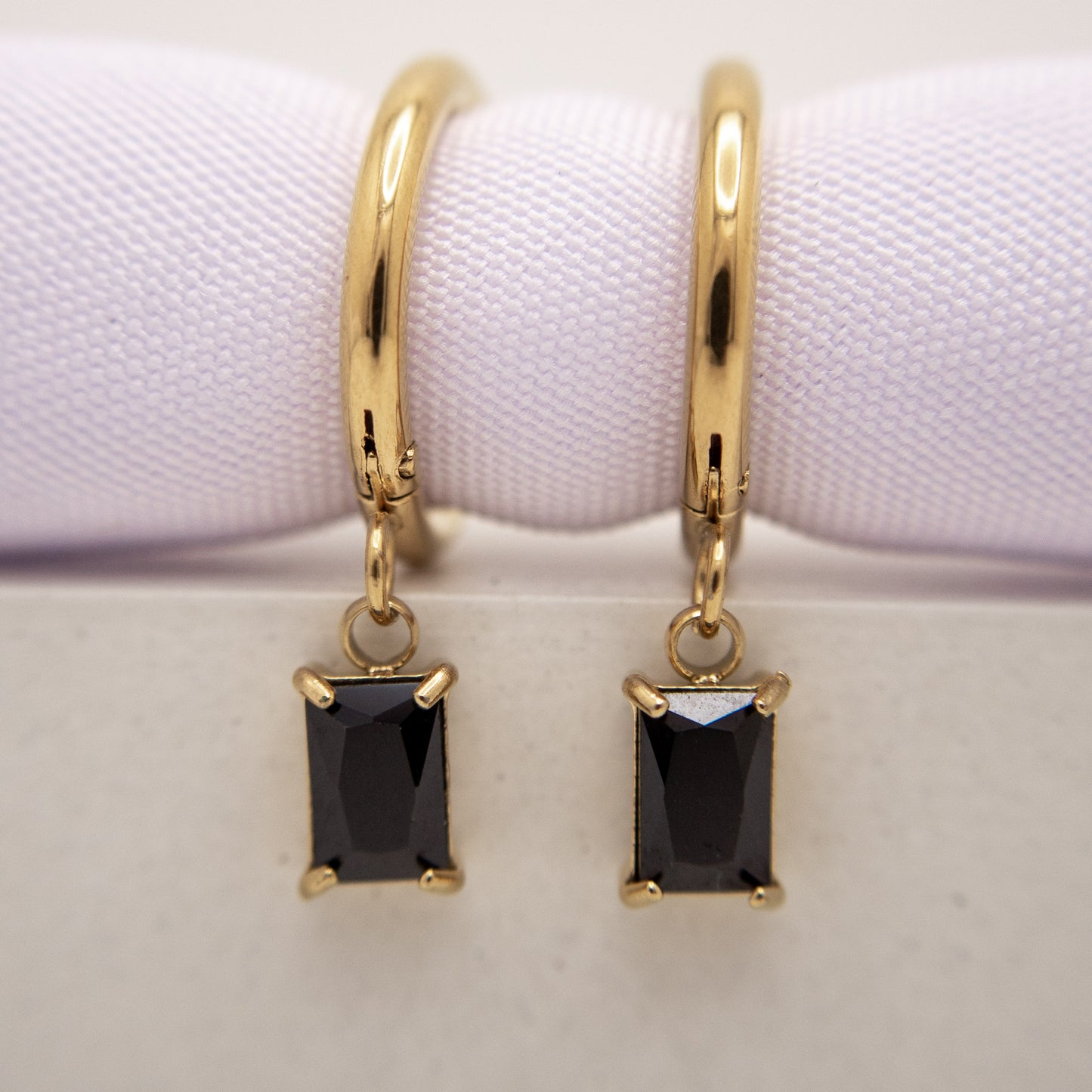 Gold hoop earrings with black gemstones on a white background