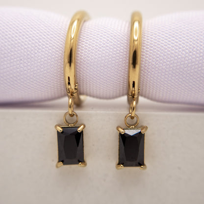 Gold hoop earrings with black gemstones on a white background