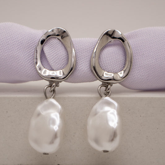 Silver earrings with pearl drops on a light purple ribbon