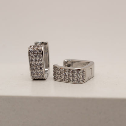 Pair of silver hoop earrings with embedded stones on a light gray background