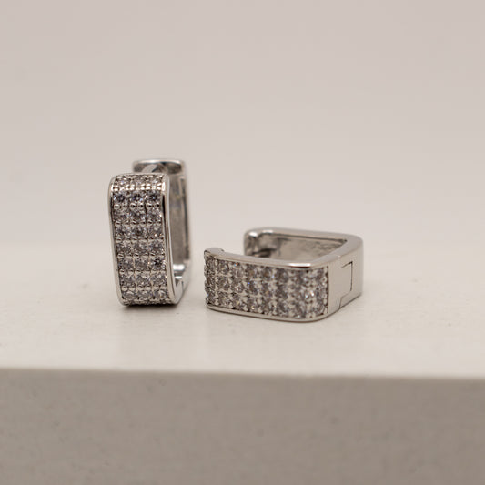 Pair of silver hoop earrings with embedded stones on a light gray background