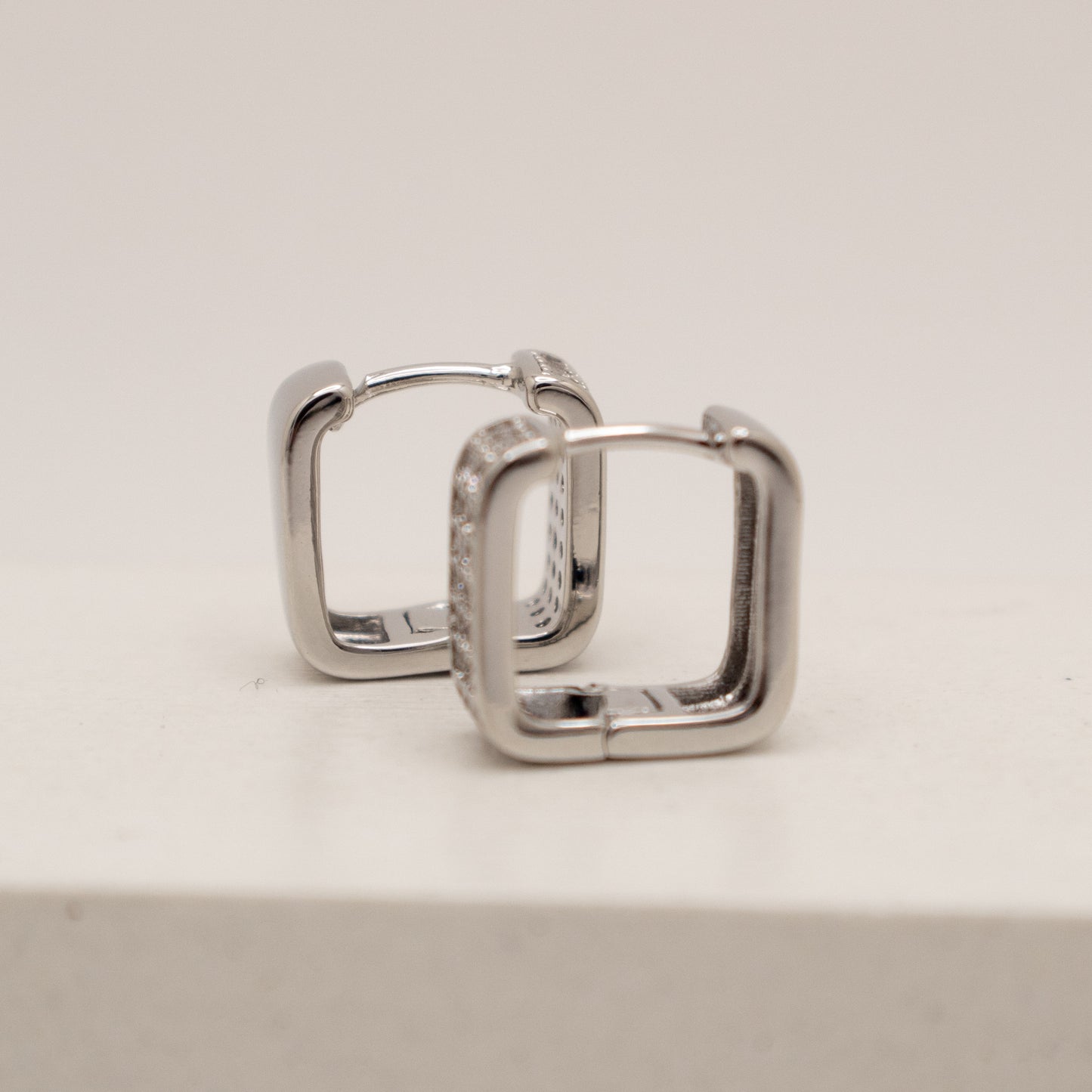 Pair of silver hoop earrings on a light gray background