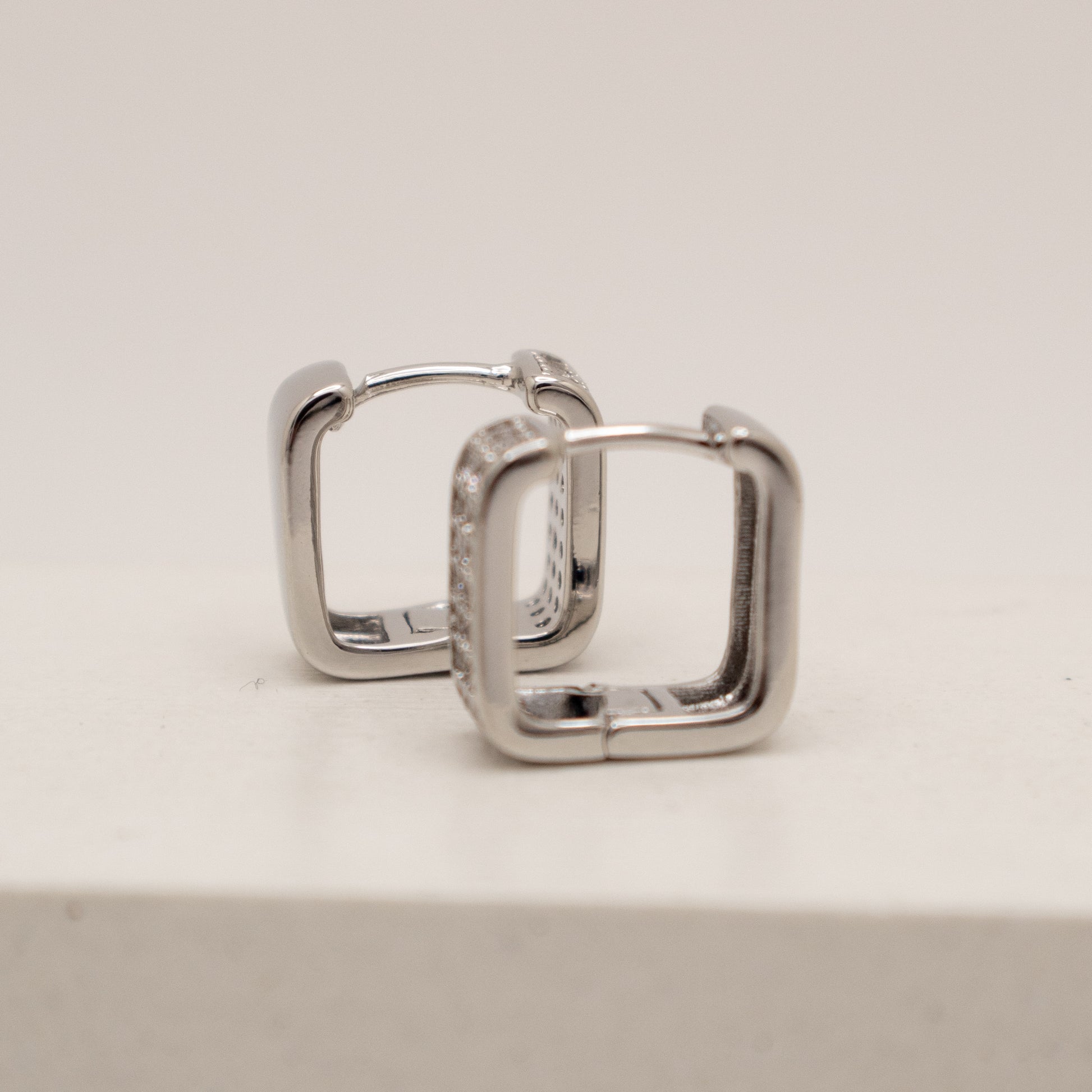Pair of silver hoop earrings on a light gray background