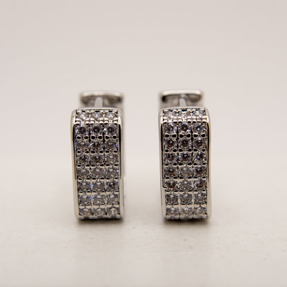 Pair of silver hoop earrings with embedded stones on a light gray background