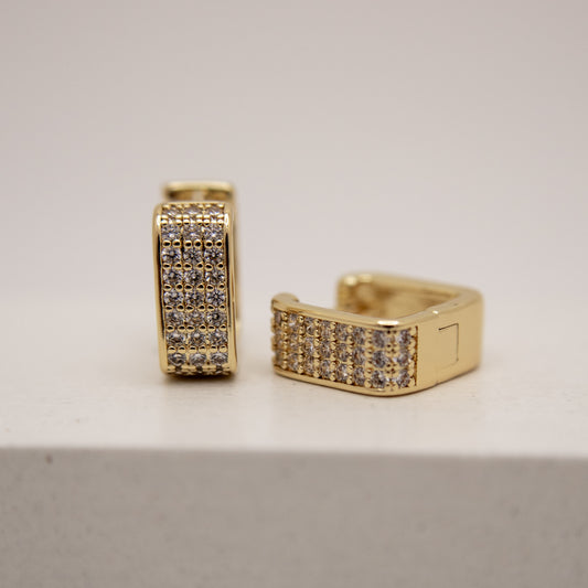 Gold hoop earrings with embedded stones on a light gray background