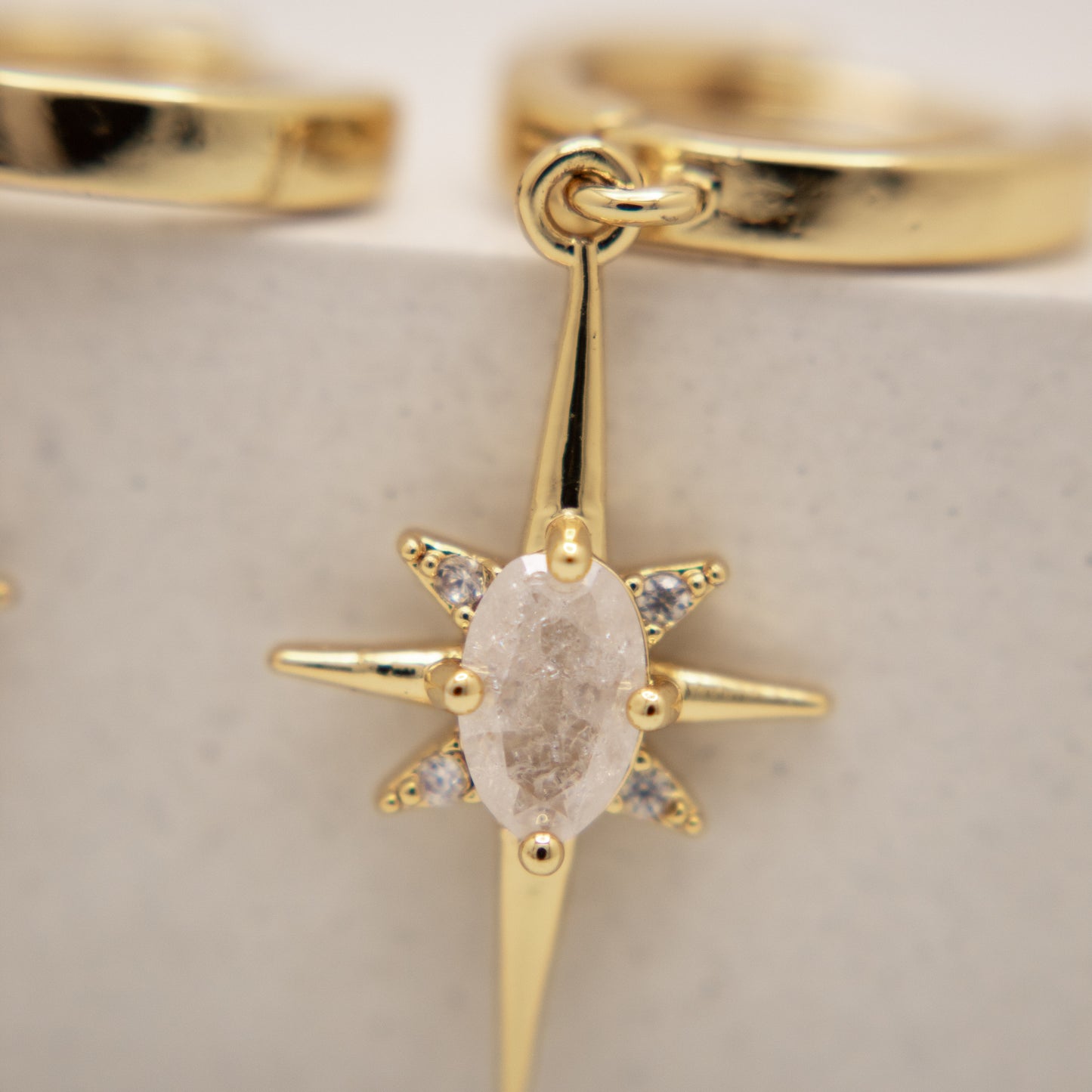 Gold ring with a star-shaped diamond pendant on a light background