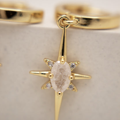 Gold ring with a star-shaped diamond pendant on a light background
