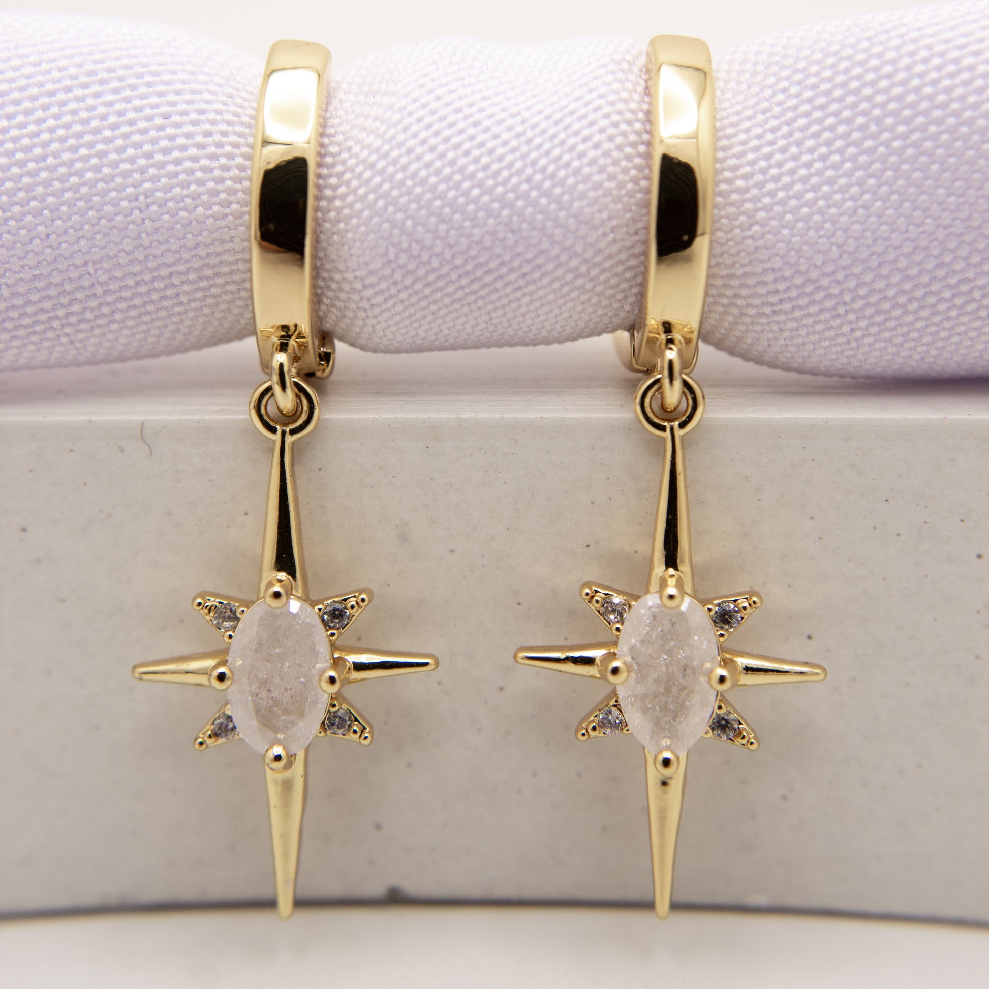 Gold earrings with star-shaped designs on a white background