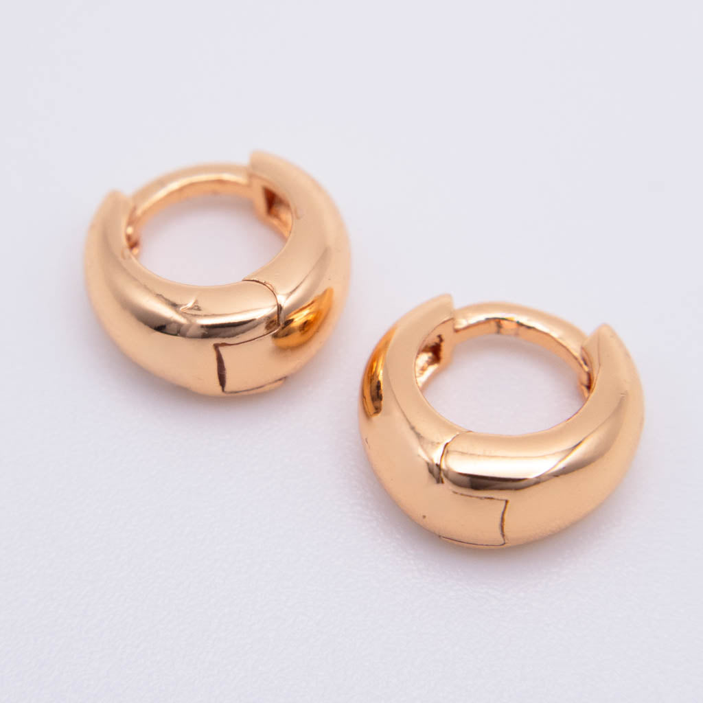 A pair of chunky, polished gold-plated huggie hoop earrings with a segmented, rounded design, displayed on a clean white background.