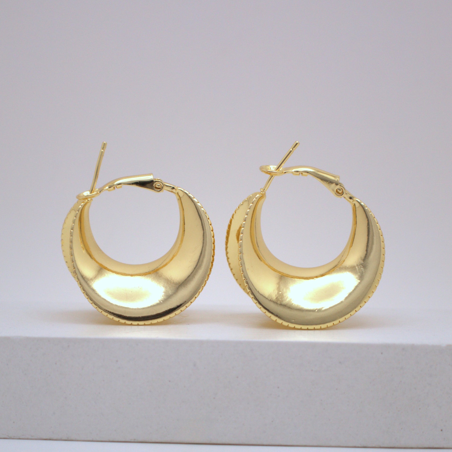 Pair of gold hoop earrings on a light gray background