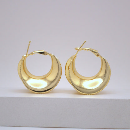 Pair of gold hoop earrings on a light gray background