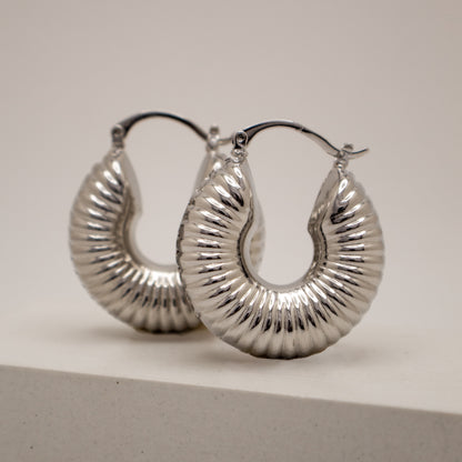 Silver hoop earrings on a light gray background