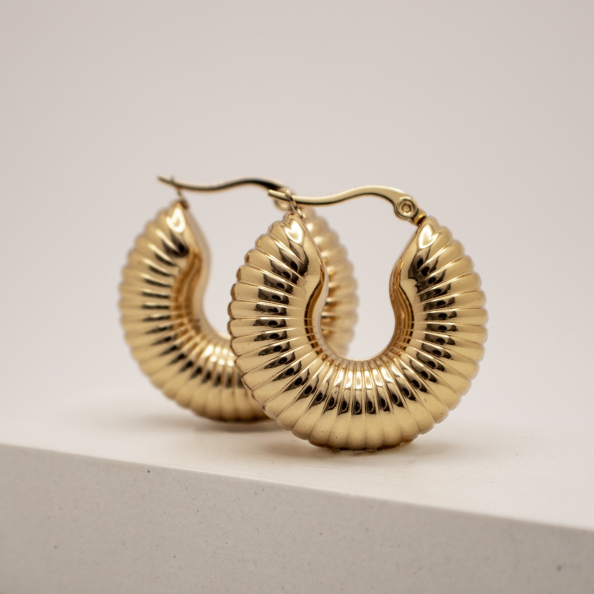 Gold hoop earrings on a light gray background