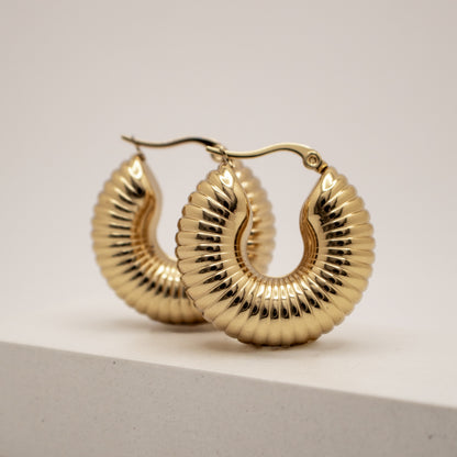 Gold hoop earrings on a light gray background