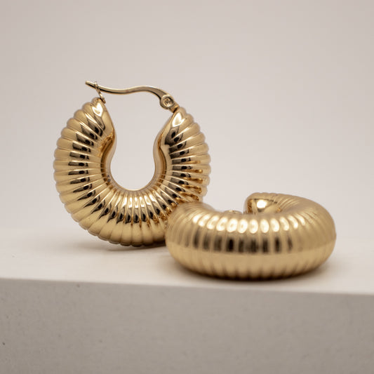 Gold hoop earrings on a light gray background