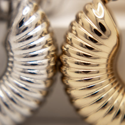 Close-up of gold and silver leaf-shaped earrings.