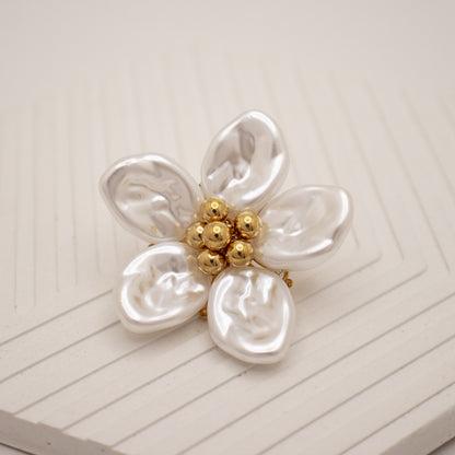 Pearl flower brooch with gold center on a white background