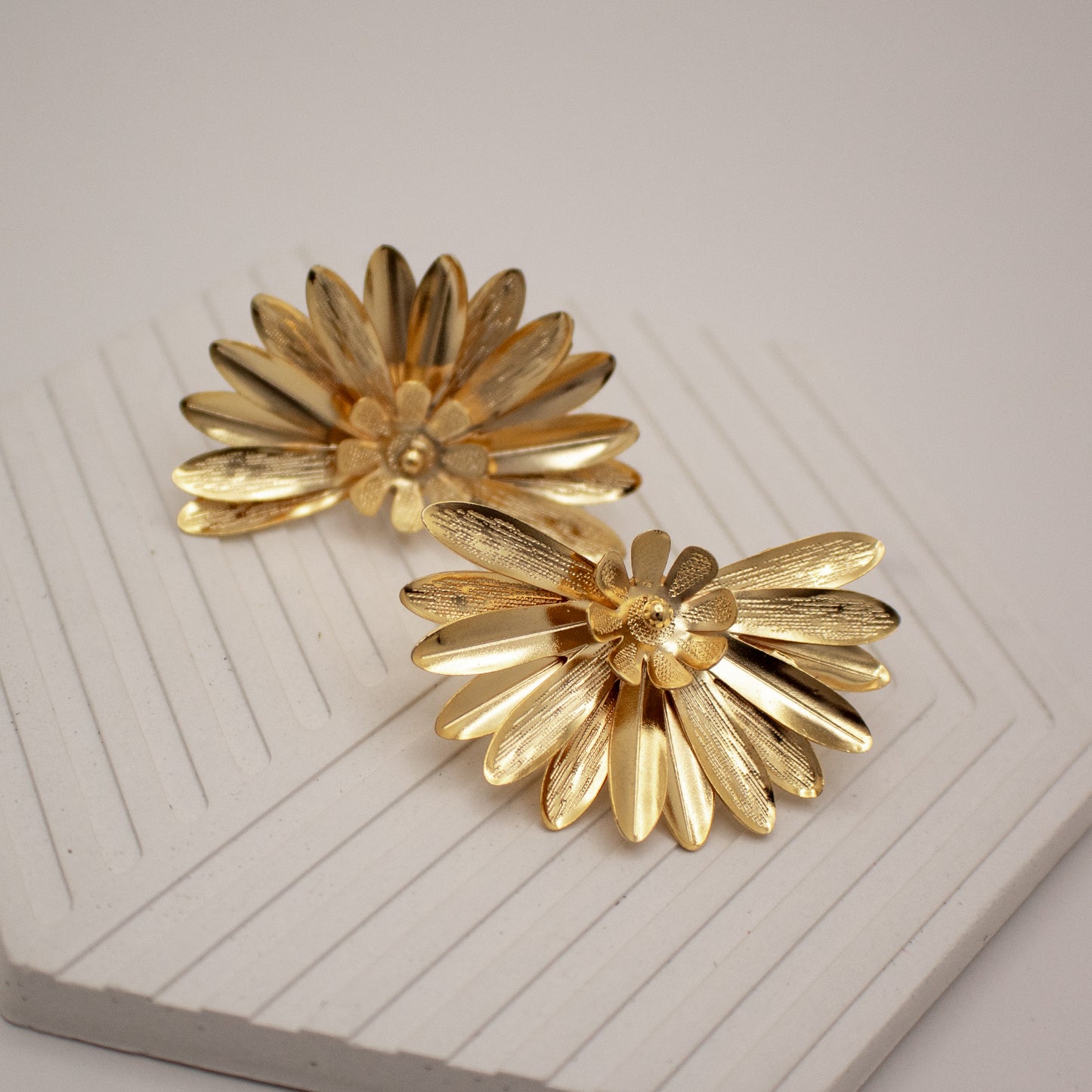 Pair of gold flower-shaped earrings on a white surface