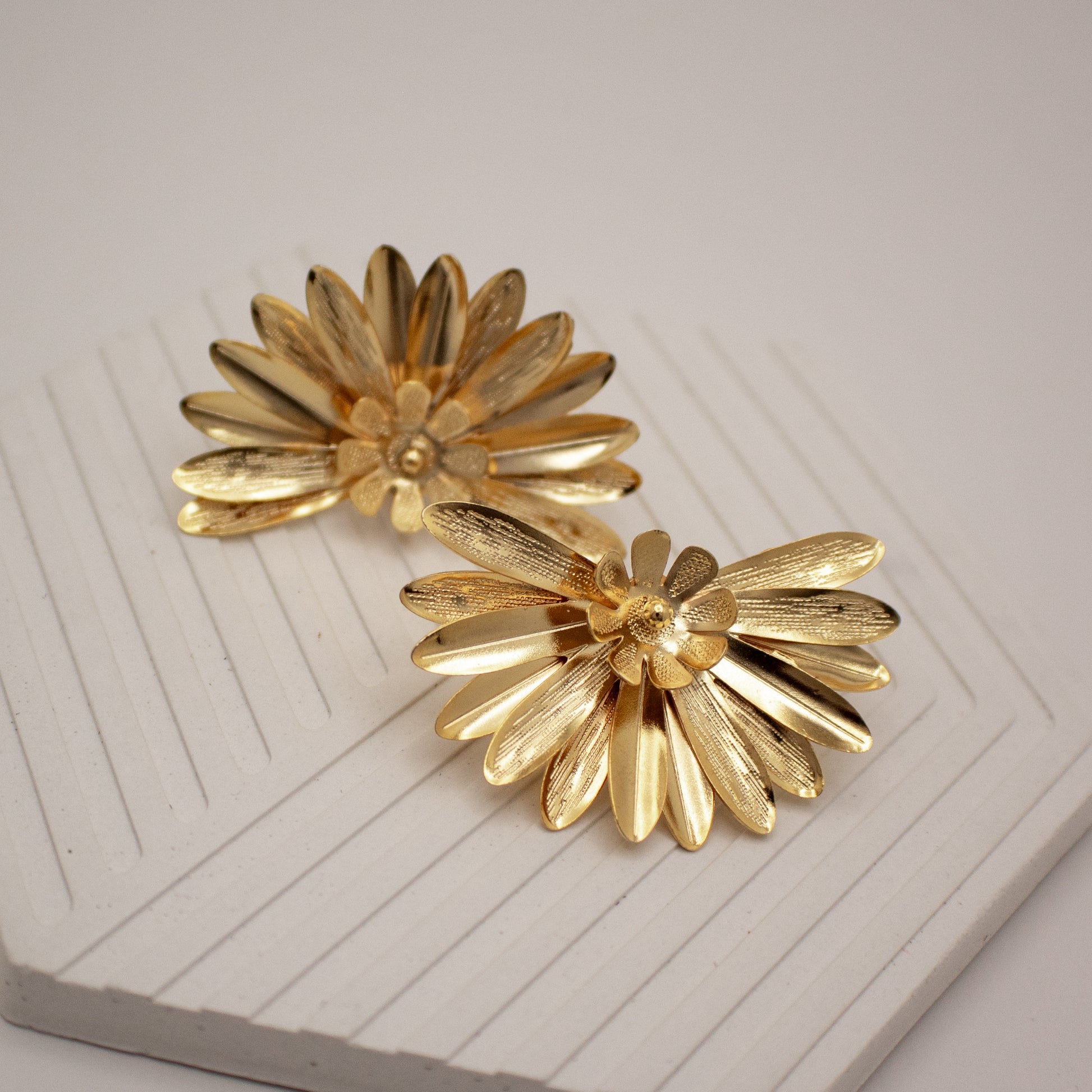 Pair of gold flower-shaped earrings on a white surface