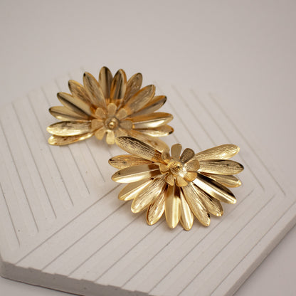 Pair of gold flower-shaped earrings on a white surface