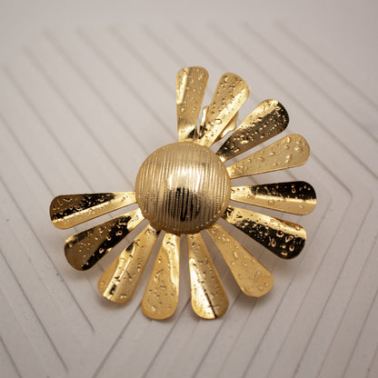 Gold sun-shaped decorative item on a textured white surface