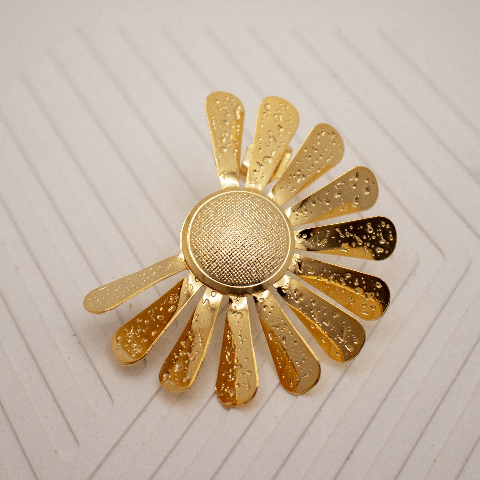 Gold sun-shaped decorative item on a white textured background