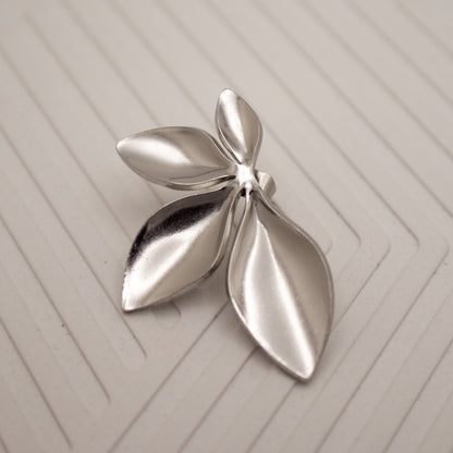 Silver leaf-shaped brooch on a textured beige surface