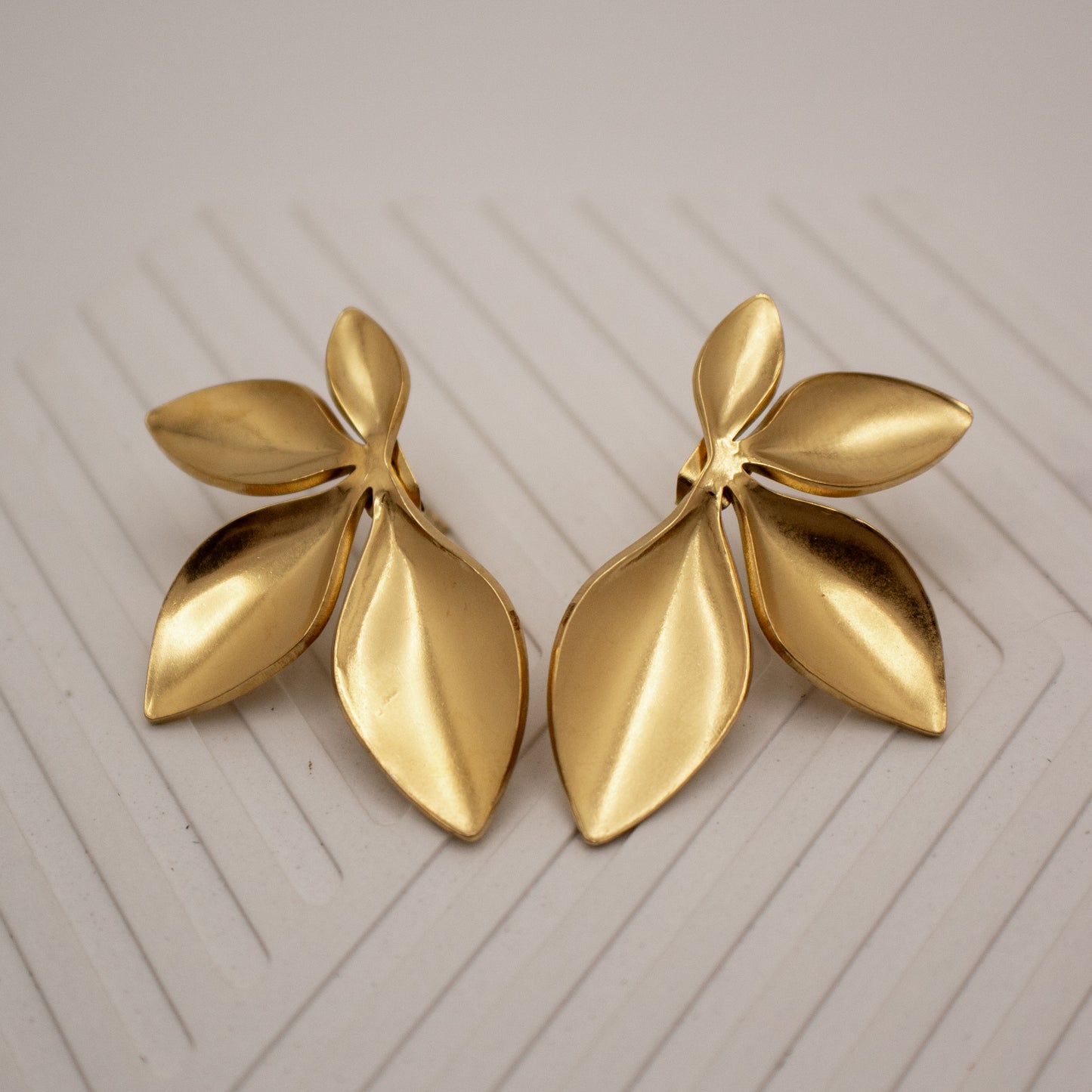 Pair of gold leaf-shaped earrings on a light background