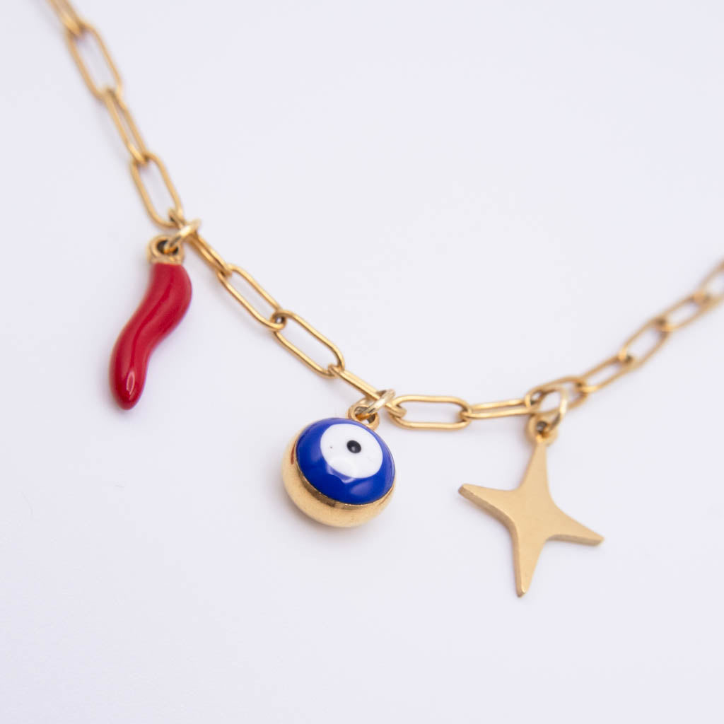 Gold chain necklace with three charms: a red italian horn, a blue and white evil eye bead, and a gold star, shown on a white background.