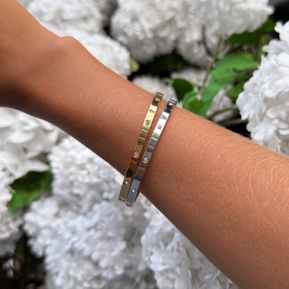 Three bracelets on a wrist with a blurred white flower background