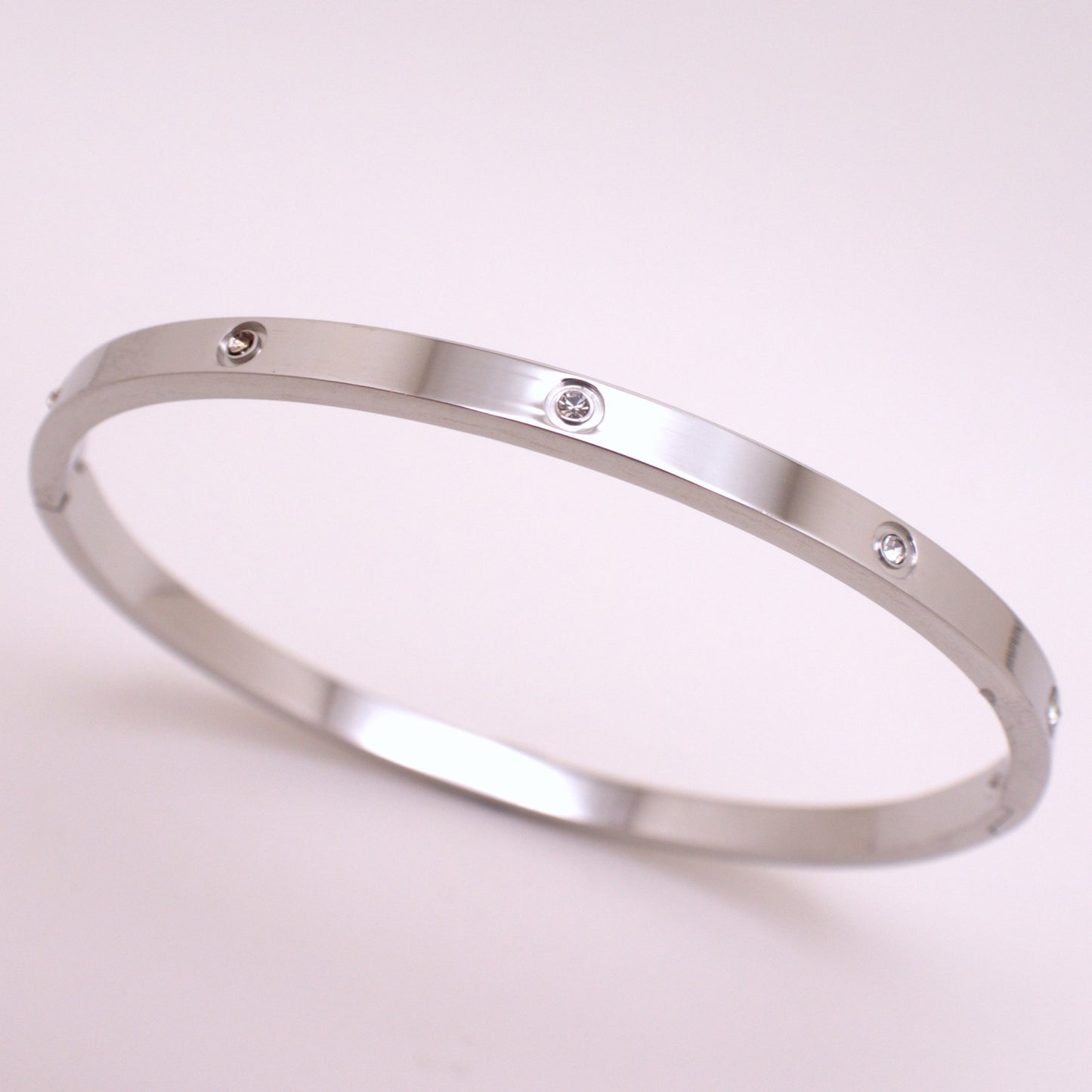 Silver bracelet with small diamonds on a light pink background