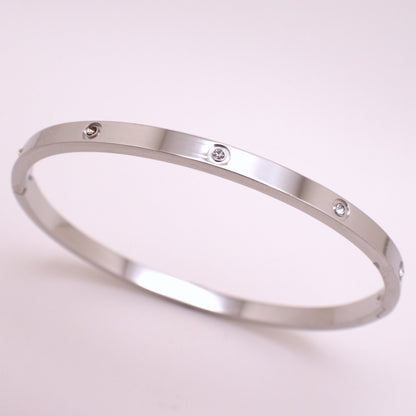 Silver bracelet with small diamonds on a light pink background