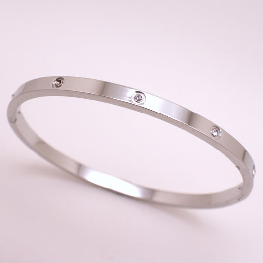 Silver bracelet with small diamonds on a light pink background