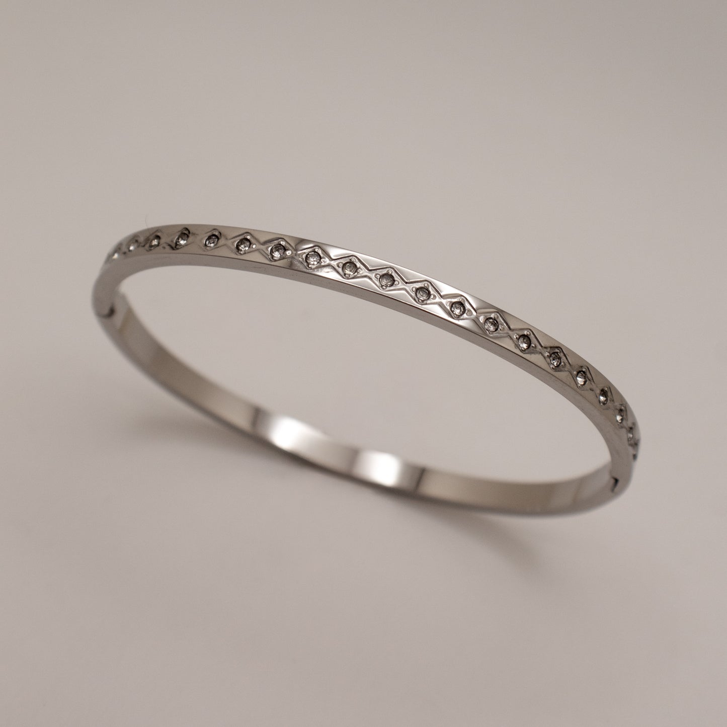 Silver ring with small stones on a light gray background