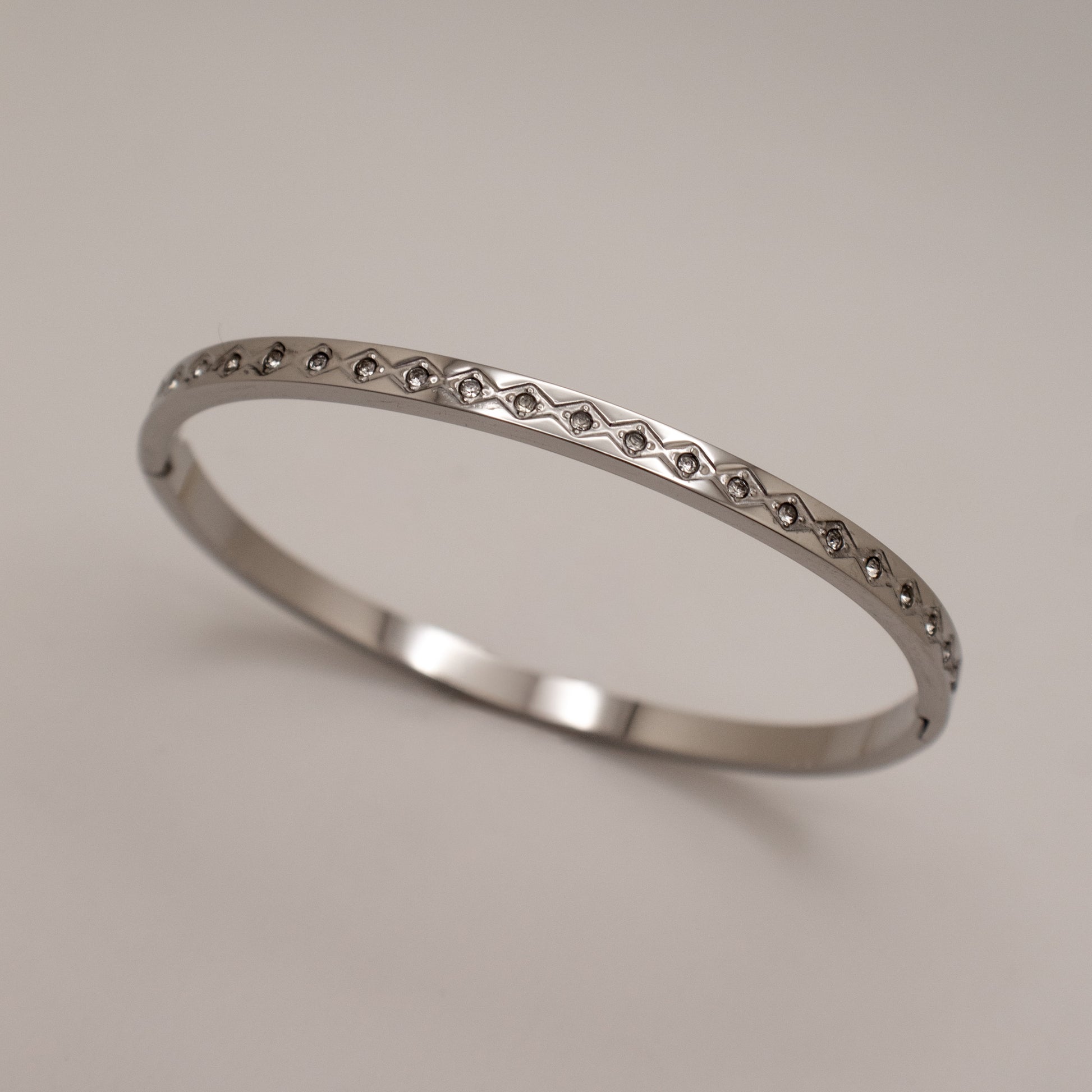 Silver ring with small stones on a light gray background