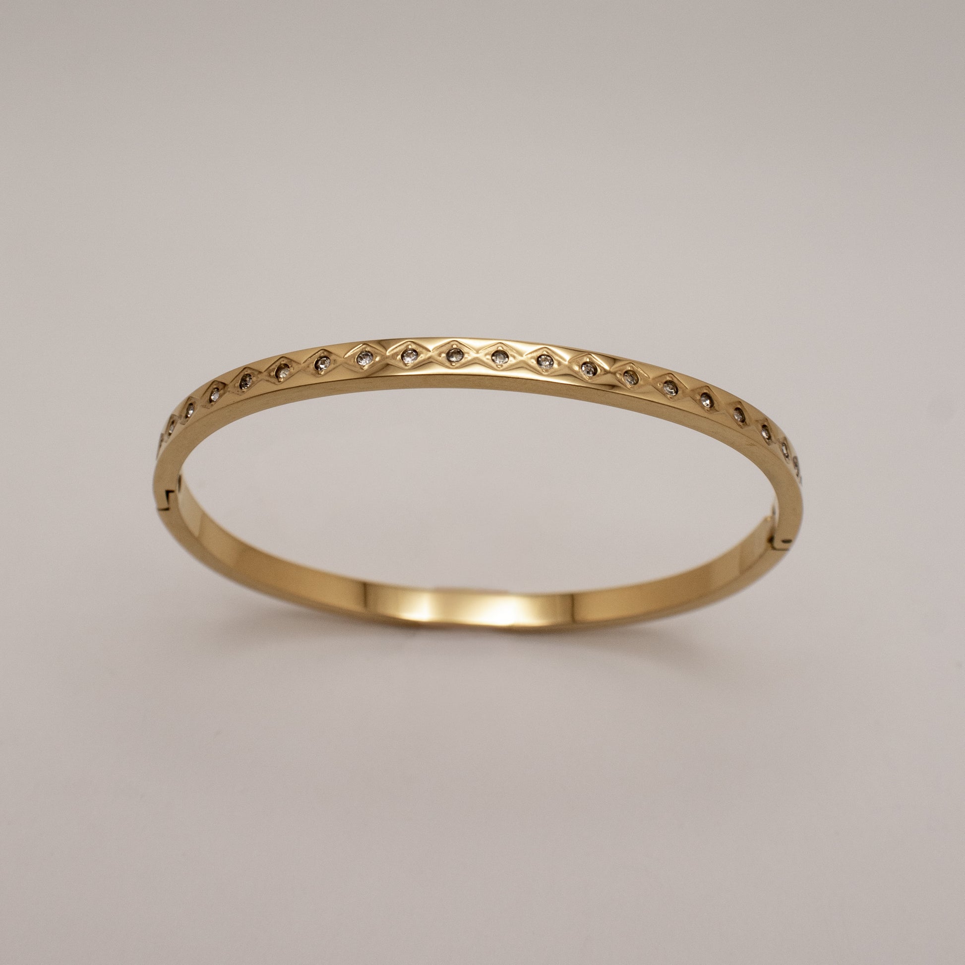 Gold ring with small diamonds on a light gray background