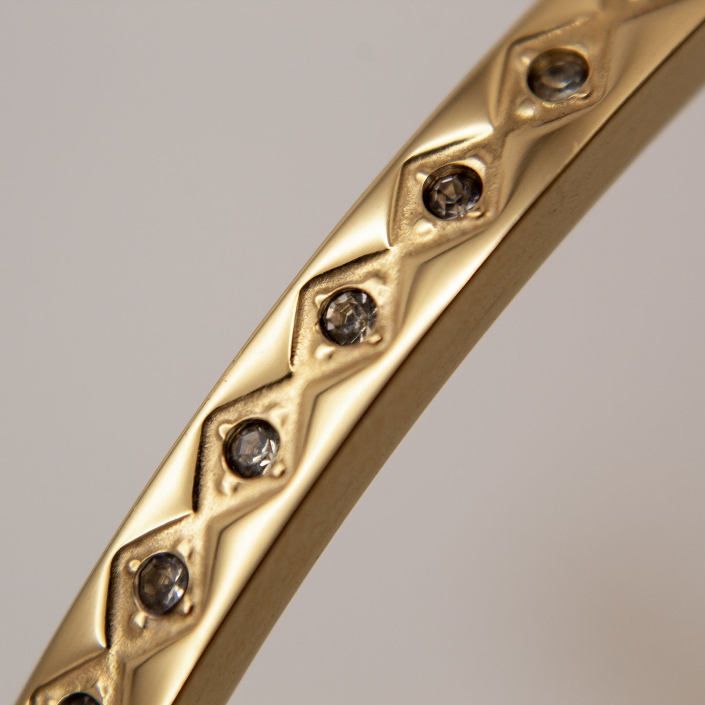 Gold bracelet with diamond-like stones on a gray background