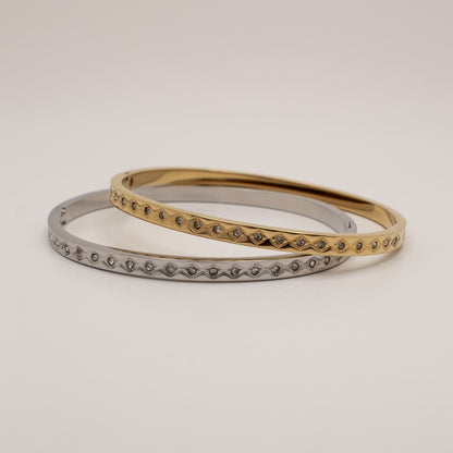 Two gold and silver bangles on a light beige background