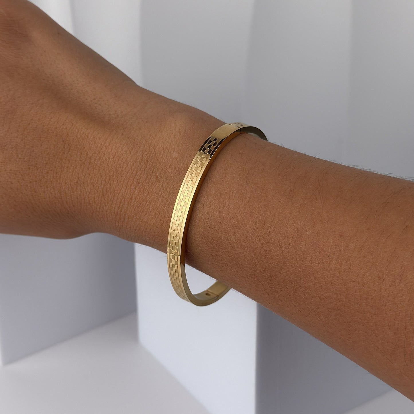 Gold bracelet on a person's wrist against a white background