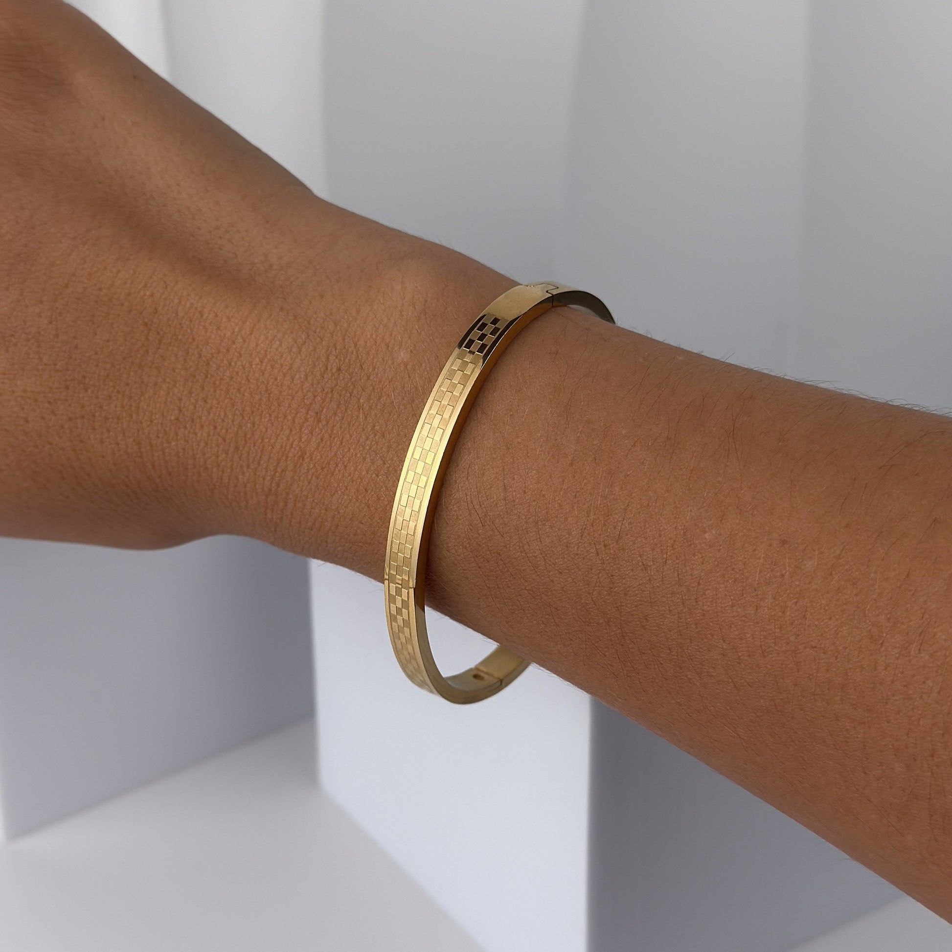 Gold bracelet on a person's wrist against a white background
