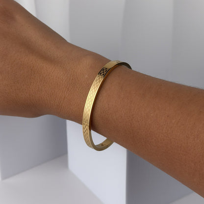 Gold bracelet on a person's wrist against a white background