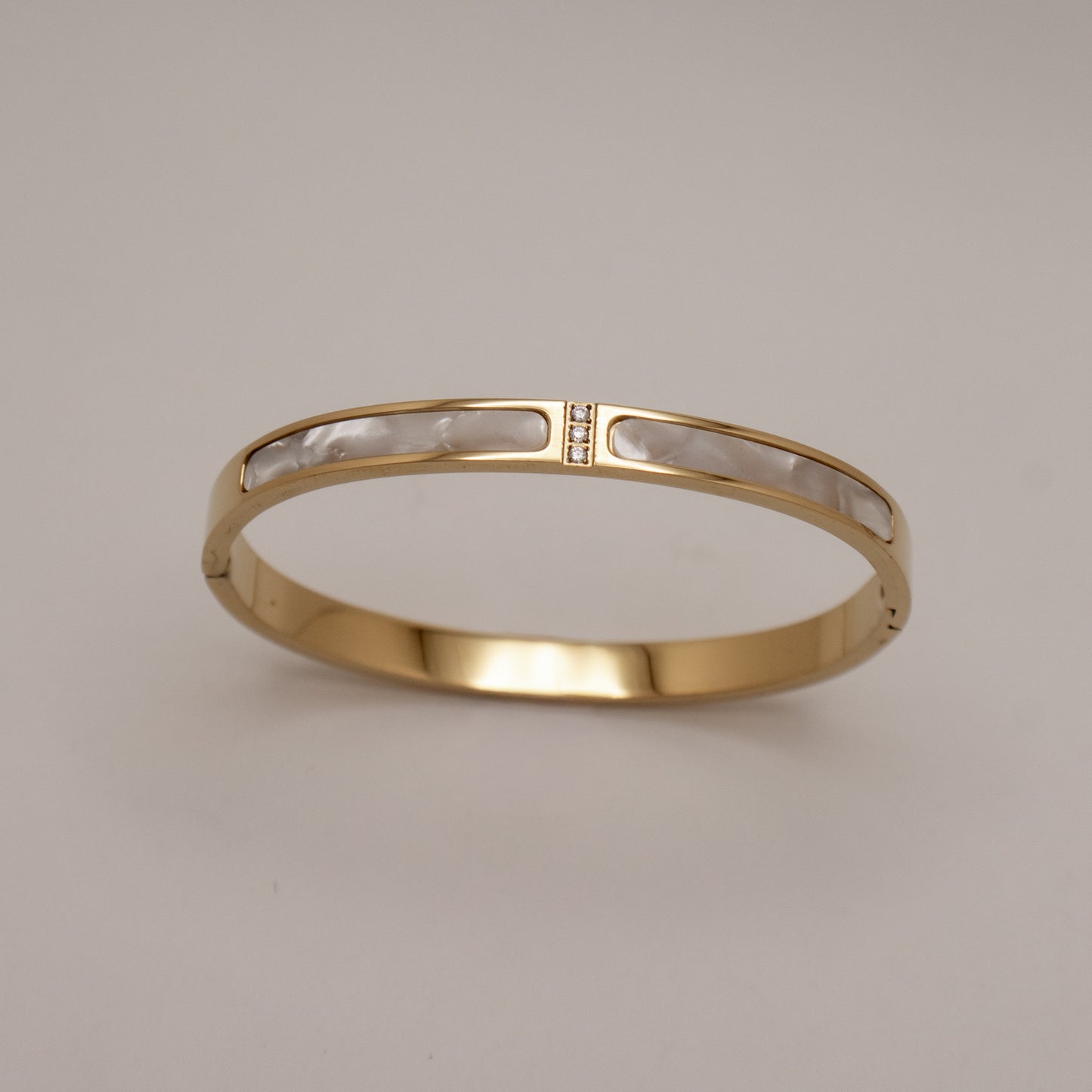 Gold bracelet with clear stones on a beige background