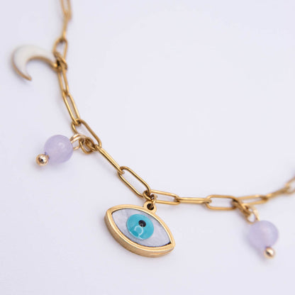 Gold chain bracelet featuring an evil eye charm with a turquoise and white iris, accented with light purple beads on a white background.