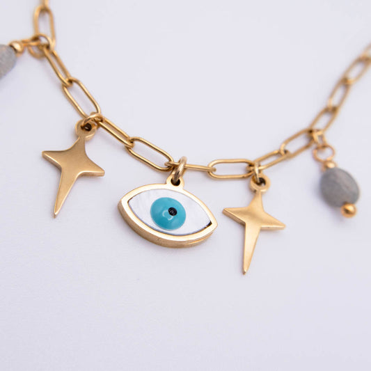 Gold-tone chain necklace with an evil eye charm, two star charms, and a small gray bead charm, shown on a light gray background.