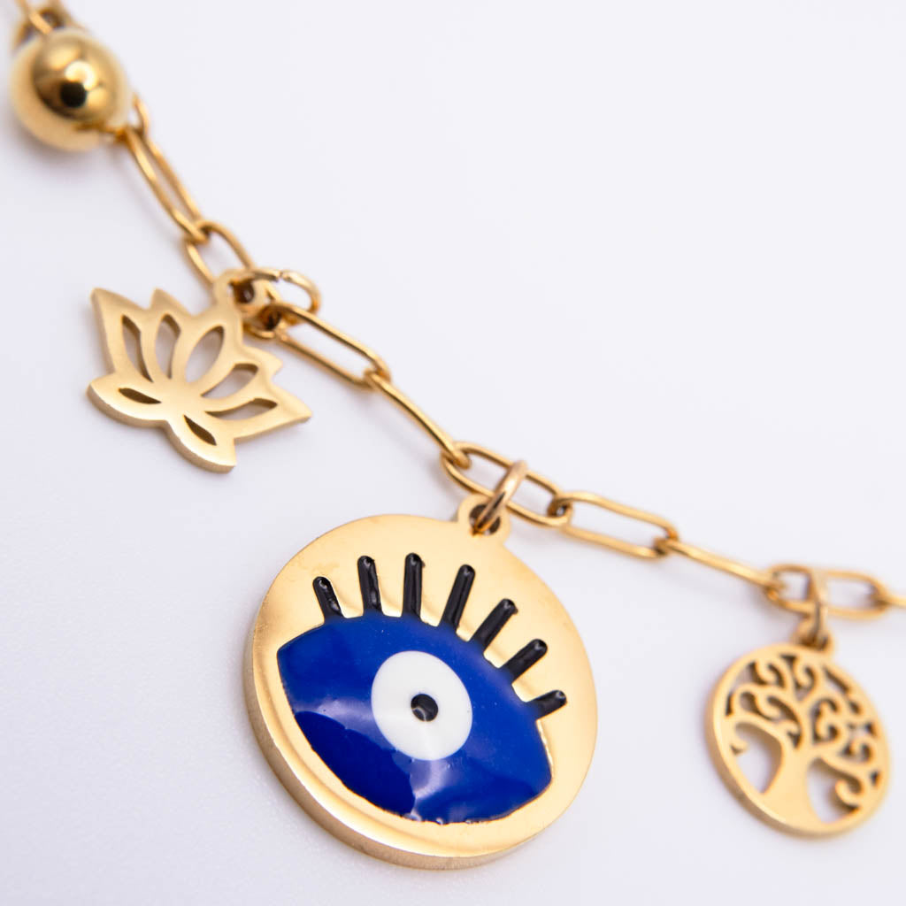 Gold-tone charm bracelet featuring a blue and white evil eye pendant, a gold lotus flower charm, and a gold tree of life charm on a white background.