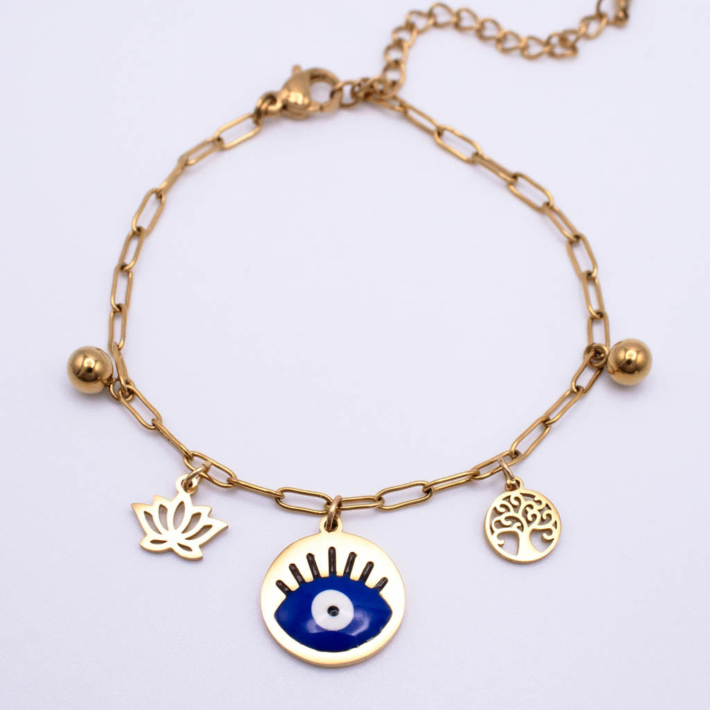 Gold chain anklet with three charms: a blue and white evil eye pendant, a gold lotus flower, and a gold tree of life, on a white background.