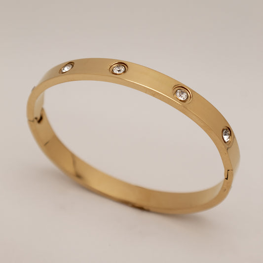 Gold bracelet with diamond-like stones on a light gray background