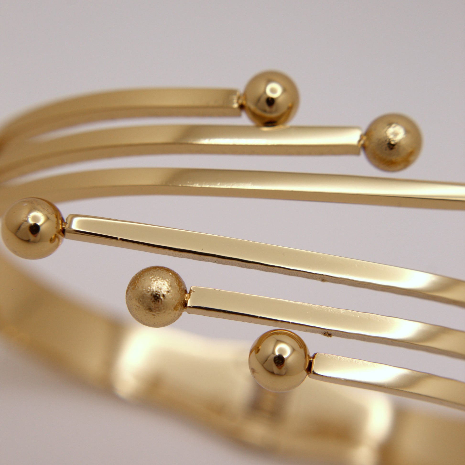 Gold bracelet with spherical beads on a light gray background